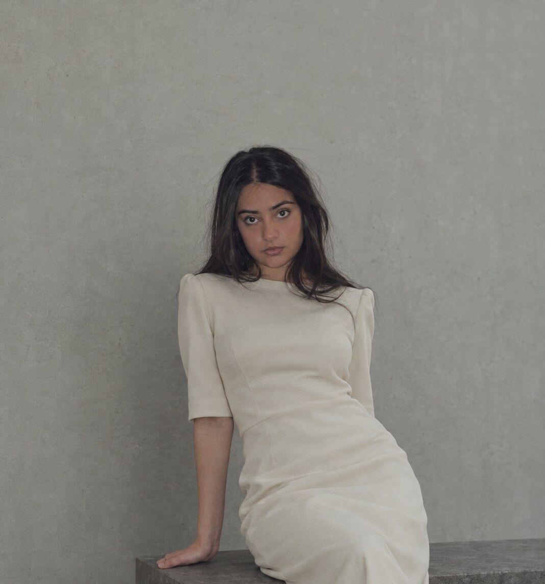 Portrait of Mehdia Haider seated against a concrete wall